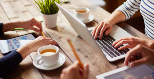 Three employees reviewing their company's finances on computers and discussing insolvency